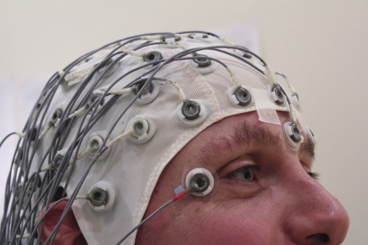 Persona con un gorro de electroencefalografía lleno de electrodos y cables sobre la cabeza
