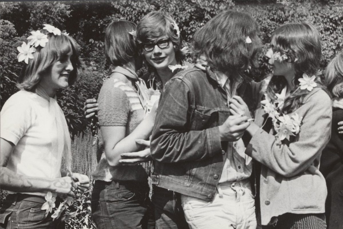 Fotografía en blanco y negro de un grupo de jóvenes con flores en el pelo y en la ropa, en un jardín, en agosto de 1967