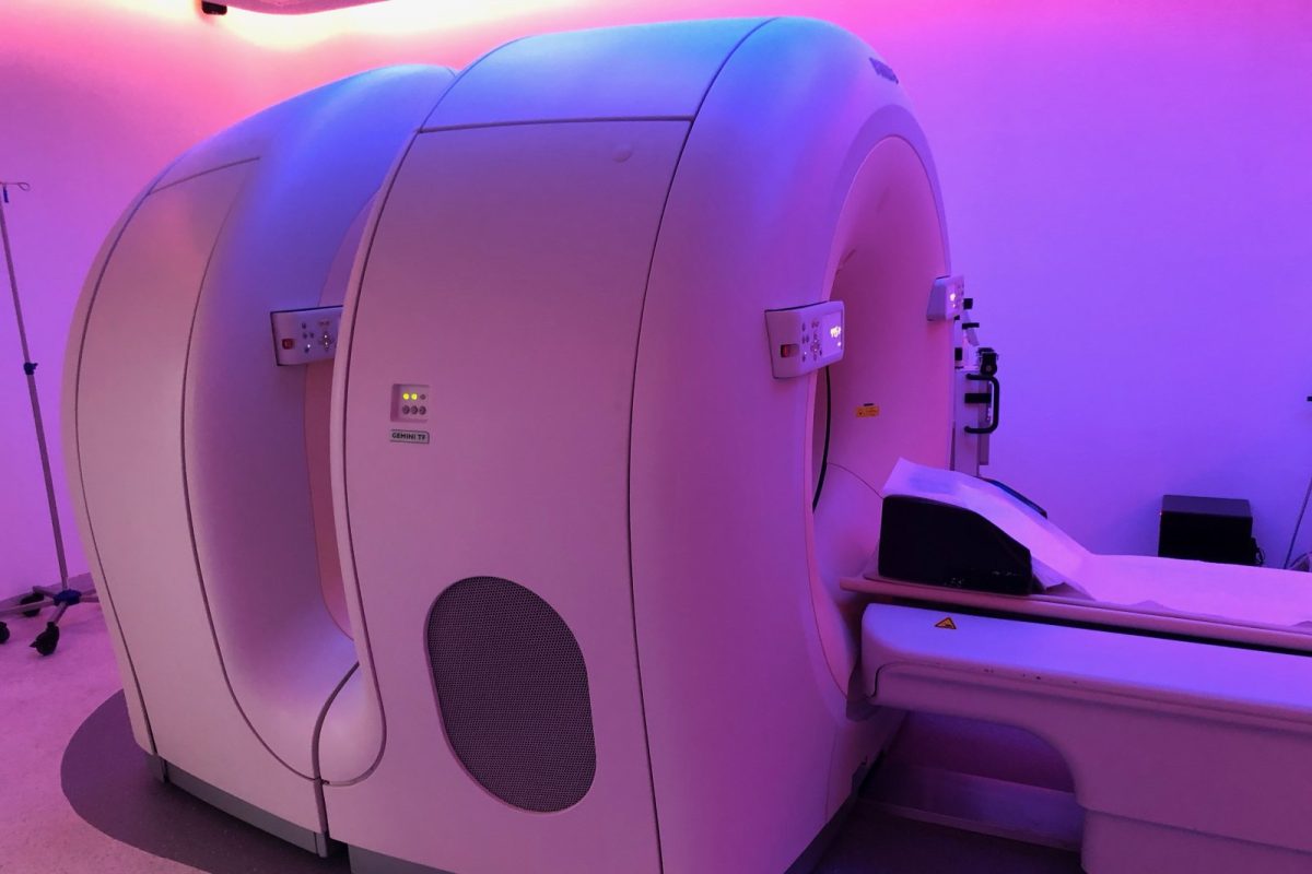 Escáner PET-TC en una sala hospitalaria con iluminación violeta y camilla de exploración extendida