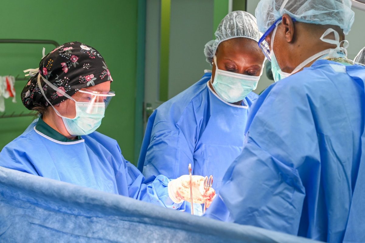 Equipo sanitario con bata, mascarilla y gorro realizando una cesárea en un quirófano hospitalario