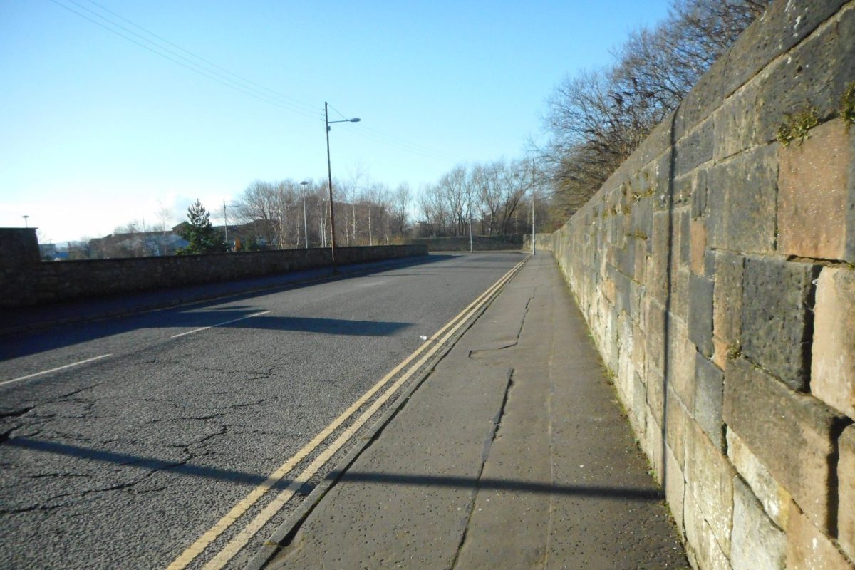 Hunter Street de Glasgow, una calle vacía junto a un muro de piedra en un día despejado